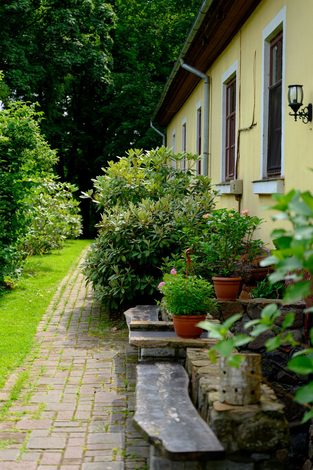 A brick path and stone benches along the manor house